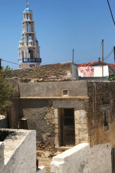 Vervallen huis met daarachter de kerktoren van Arkasa Karpathos Griekenland