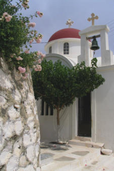 Bloemenpracht in een steeg met een kapel op de achtergrond